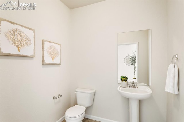 half bathroom with baseboards and toilet