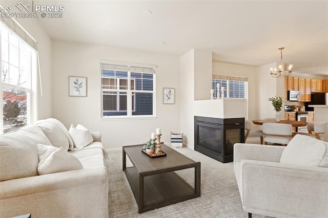 living area featuring light carpet, baseboards, a multi sided fireplace, and a chandelier