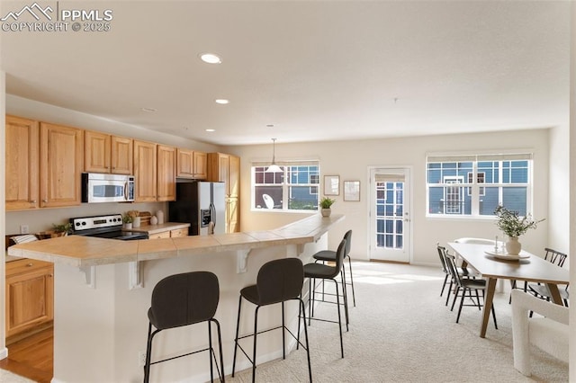 kitchen featuring a breakfast bar area, recessed lighting, light carpet, appliances with stainless steel finishes, and pendant lighting