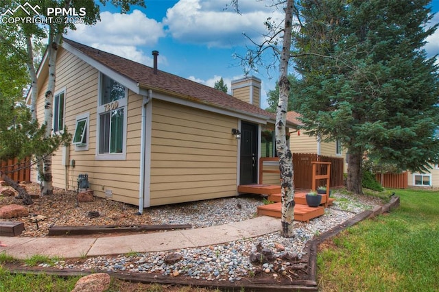 exterior space featuring a chimney, a front yard, a wooden deck, and fence