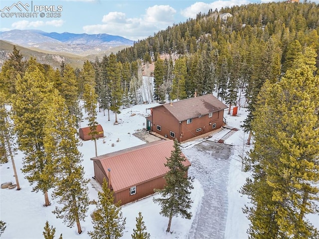 snowy aerial view featuring a mountain view and a forest view