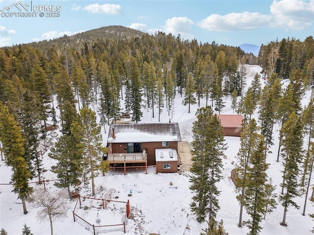 snowy aerial view with a mountain view and a wooded view