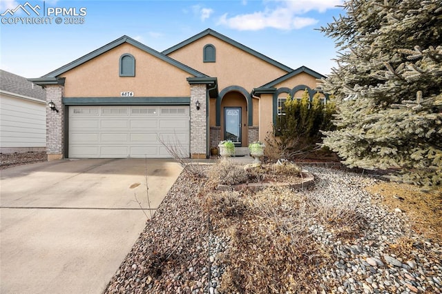 view of front of property with concrete driveway, brick siding, an attached garage, and stucco siding