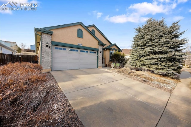 ranch-style house featuring a garage, concrete driveway, fence, and stucco siding