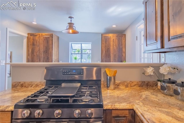 kitchen with light stone countertops, brown cabinetry, range with gas stovetop, and recessed lighting