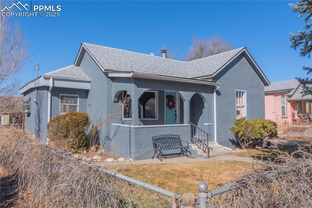 view of front of property with a porch, roof with shingles, and stucco siding