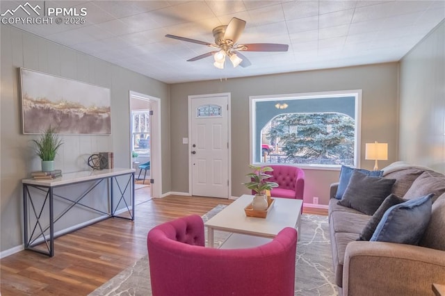 living room with a ceiling fan, plenty of natural light, baseboards, and wood finished floors