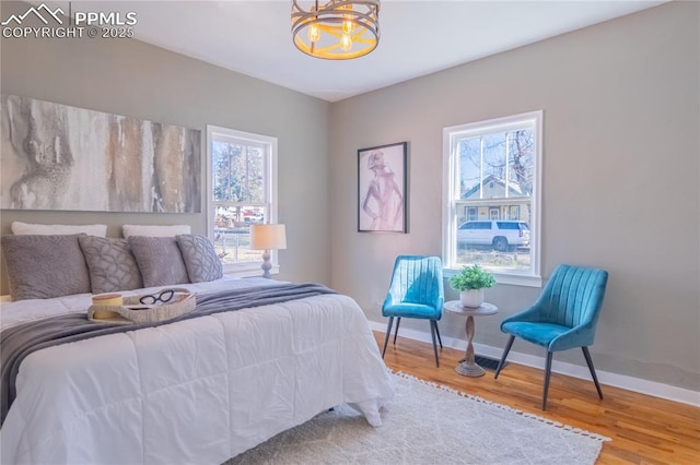 bedroom with multiple windows, a notable chandelier, baseboards, and wood finished floors