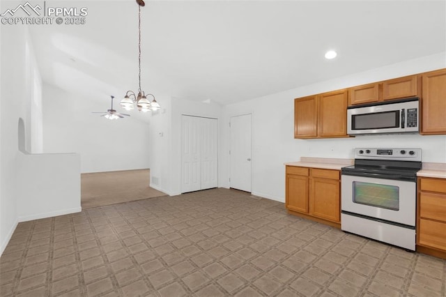 kitchen with a notable chandelier, electric range, light countertops, stainless steel microwave, and pendant lighting