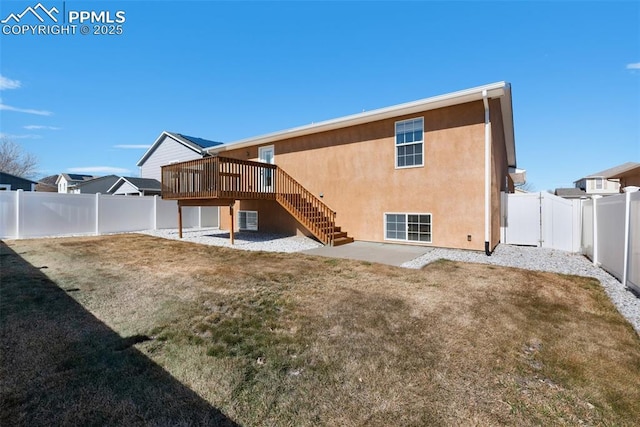 back of house featuring stucco siding, a fenced backyard, a yard, and stairs