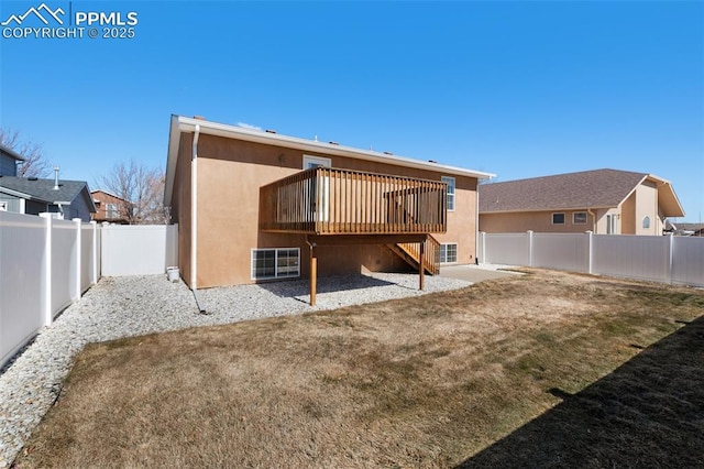 back of property with stucco siding, a lawn, a fenced backyard, a wooden deck, and stairs