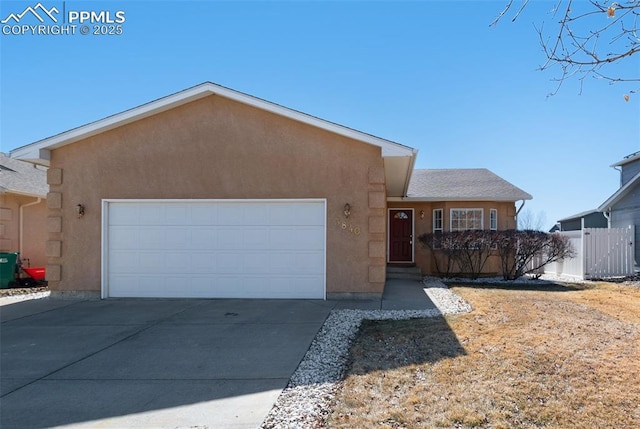 view of front of house with a garage, driveway, fence, and stucco siding