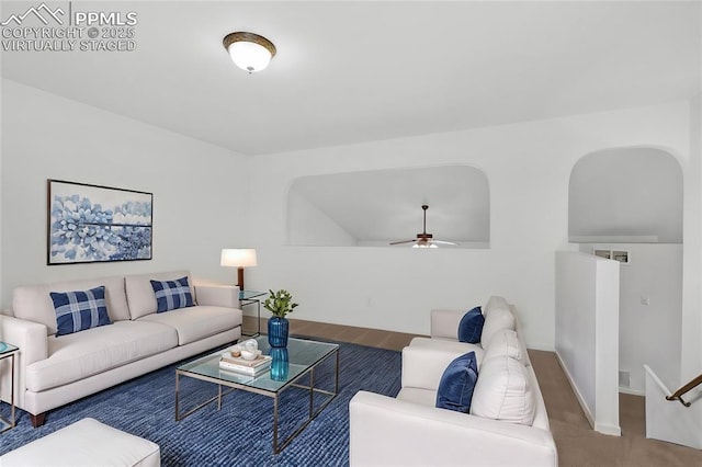 living room with arched walkways, ceiling fan, and baseboards