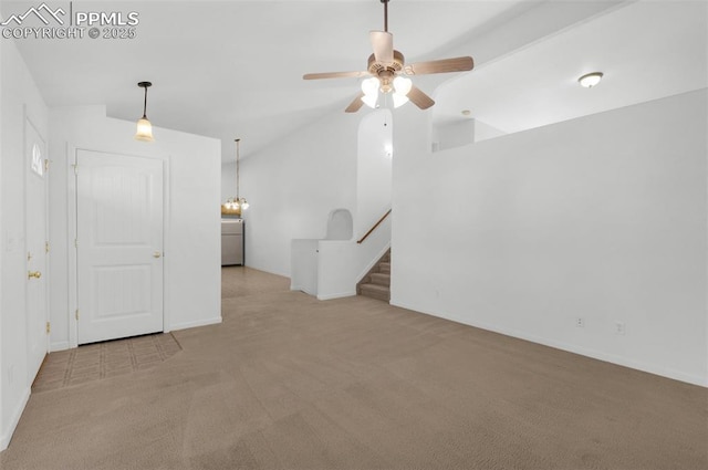 carpeted empty room featuring vaulted ceiling, washer / dryer, stairway, and a ceiling fan