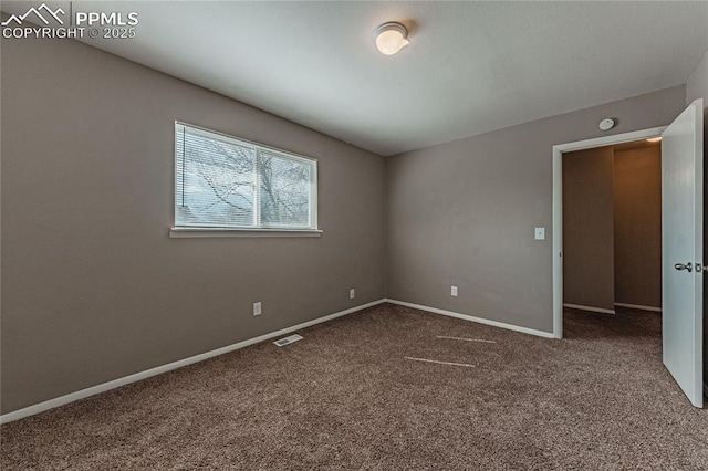 spare room featuring carpet, visible vents, and baseboards