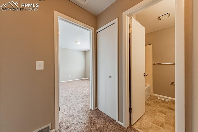 corridor featuring baseboards, visible vents, and light colored carpet