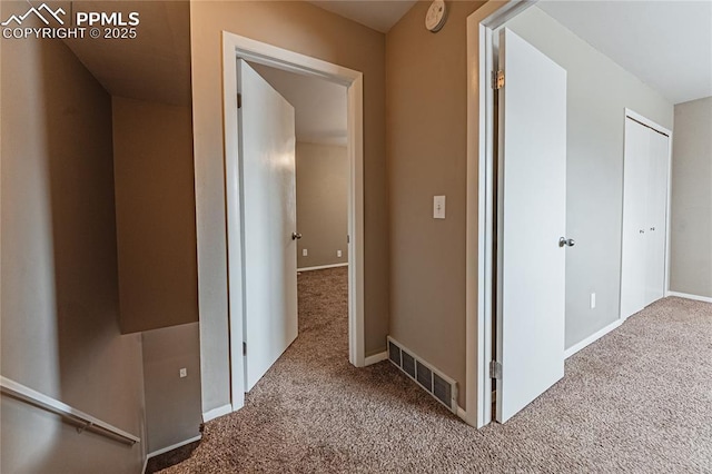 corridor with carpet floors, visible vents, and baseboards