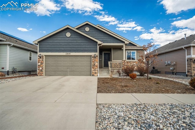 view of front facade with a garage, concrete driveway, central AC, and stone siding