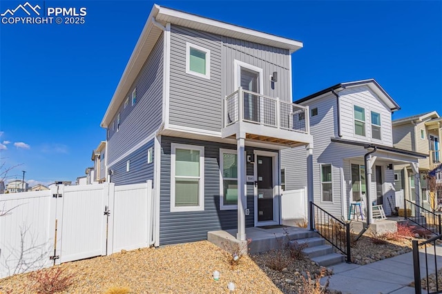 view of front of house featuring a gate, fence, and a balcony