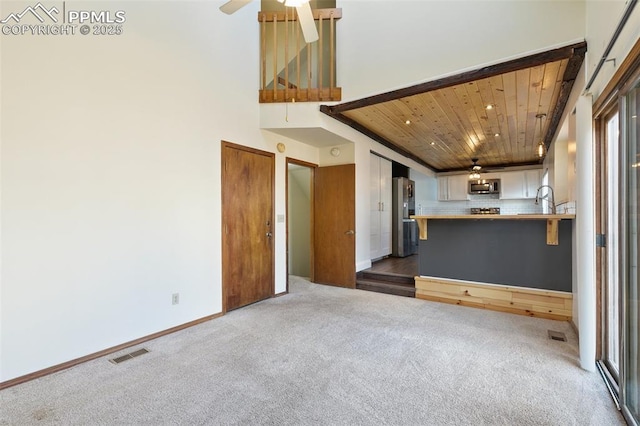 unfurnished living room featuring carpet, visible vents, ceiling fan, wooden ceiling, and baseboards