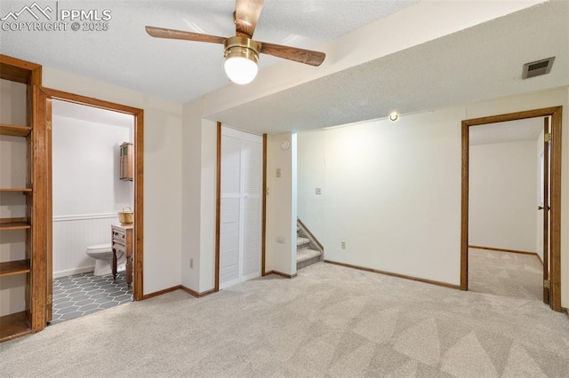 unfurnished bedroom with ensuite bath, visible vents, a textured ceiling, and light colored carpet