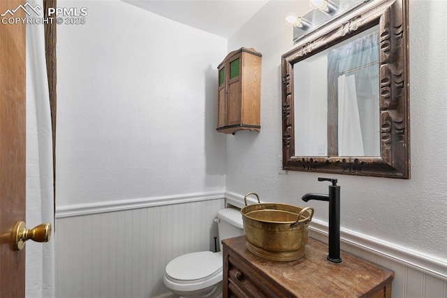 bathroom with wainscoting and toilet