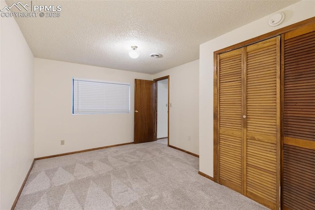 unfurnished bedroom with baseboards, a closet, a textured ceiling, and light colored carpet