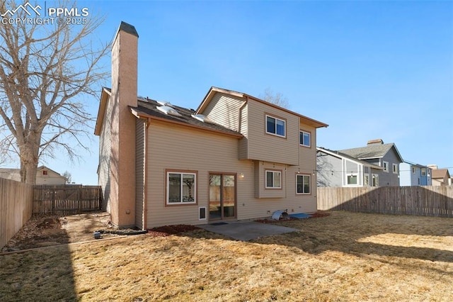 back of house with a yard, a chimney, a patio area, and a fenced backyard