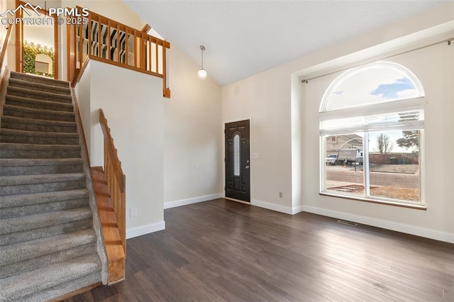 foyer with high vaulted ceiling, dark wood-type flooring, stairway, and baseboards