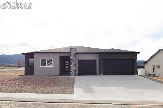 prairie-style house with concrete driveway, central AC unit, an attached garage, and stucco siding