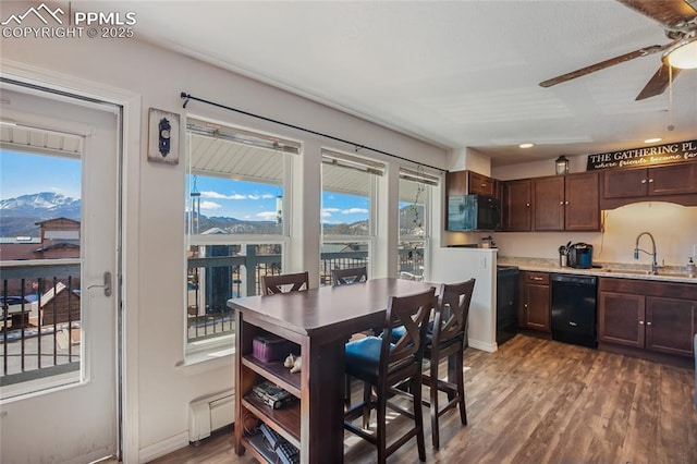 kitchen featuring a mountain view, dark wood-type flooring, a sink, light countertops, and black appliances