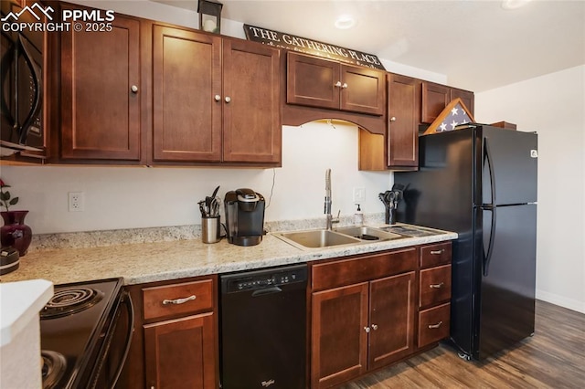 kitchen featuring black appliances, light stone counters, a sink, and wood finished floors