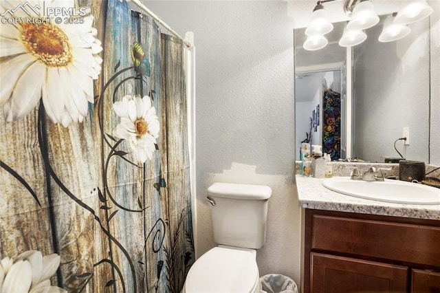 full bath with a textured wall, vanity, and toilet