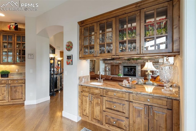 bar with arched walkways, a sink, baseboards, and wood finished floors