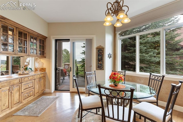 dining room with light wood-style floors, a healthy amount of sunlight, a notable chandelier, and baseboards