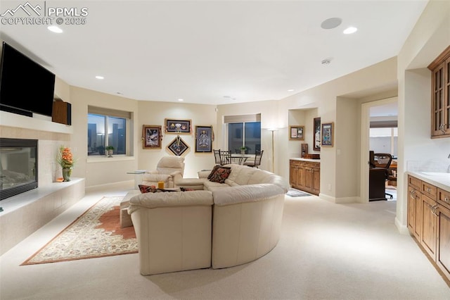 living room with recessed lighting, baseboards, light colored carpet, and a tile fireplace