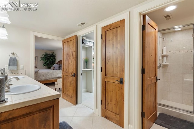 full bathroom with visible vents, ensuite bathroom, a stall shower, a sink, and tile patterned flooring