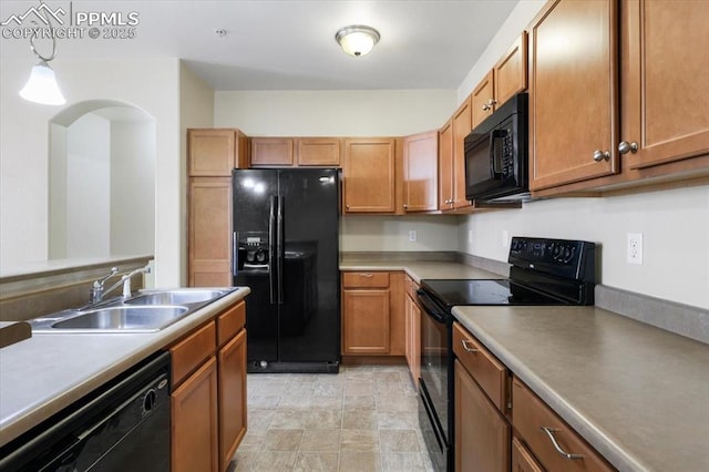 kitchen with decorative light fixtures, light countertops, brown cabinetry, a sink, and black appliances