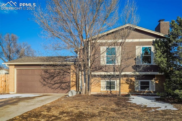 split level home with brick siding, driveway, a chimney, and an attached garage