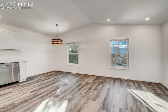 unfurnished dining area featuring lofted ceiling, light wood-style floors, baseboards, and recessed lighting