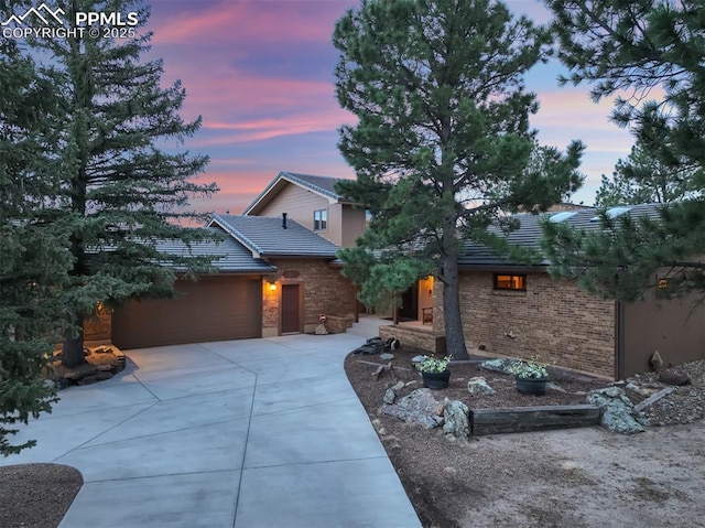 view of front of house featuring driveway, an attached garage, and a tile roof