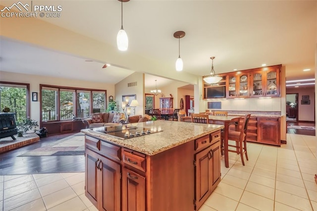 kitchen with light tile patterned floors, lofted ceiling, open floor plan, a wood stove, and black electric cooktop