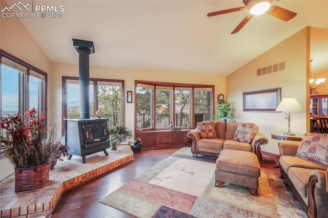 living area featuring a wood stove, hardwood / wood-style flooring, visible vents, and lofted ceiling