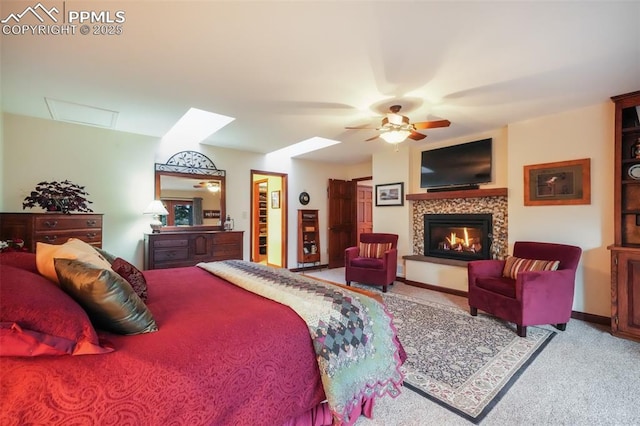 bedroom with carpet floors, a glass covered fireplace, ceiling fan, and baseboards