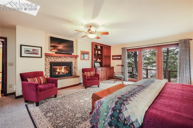 bedroom with access to exterior, a glass covered fireplace, baseboards, and carpet