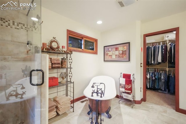 bathroom with a stall shower, a soaking tub, and a walk in closet