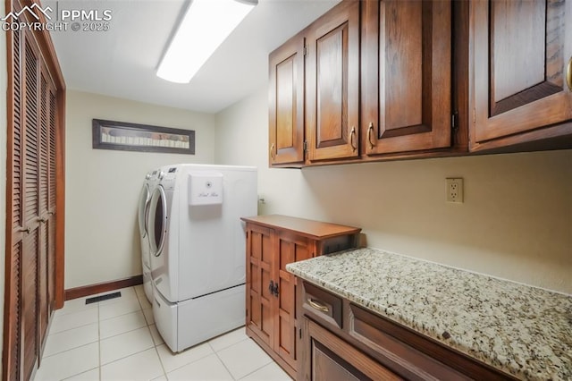 laundry area featuring cabinet space, light tile patterned floors, baseboards, visible vents, and washing machine and clothes dryer