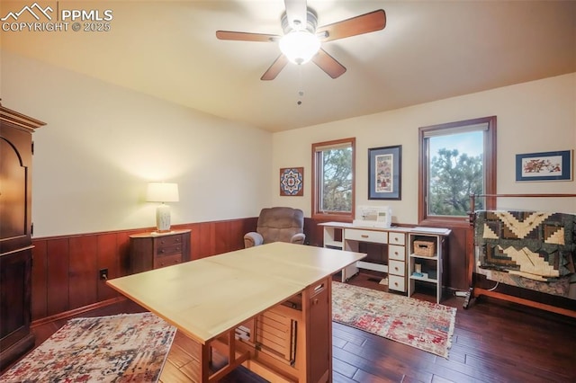 office space with a wainscoted wall, dark wood-style flooring, a ceiling fan, and wooden walls