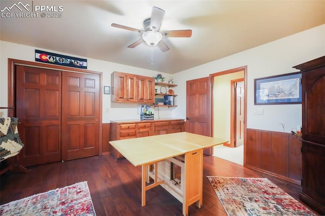 dining space with dark wood-style flooring, wainscoting, and ceiling fan