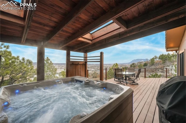 wooden deck featuring a hot tub, a mountain view, and grilling area